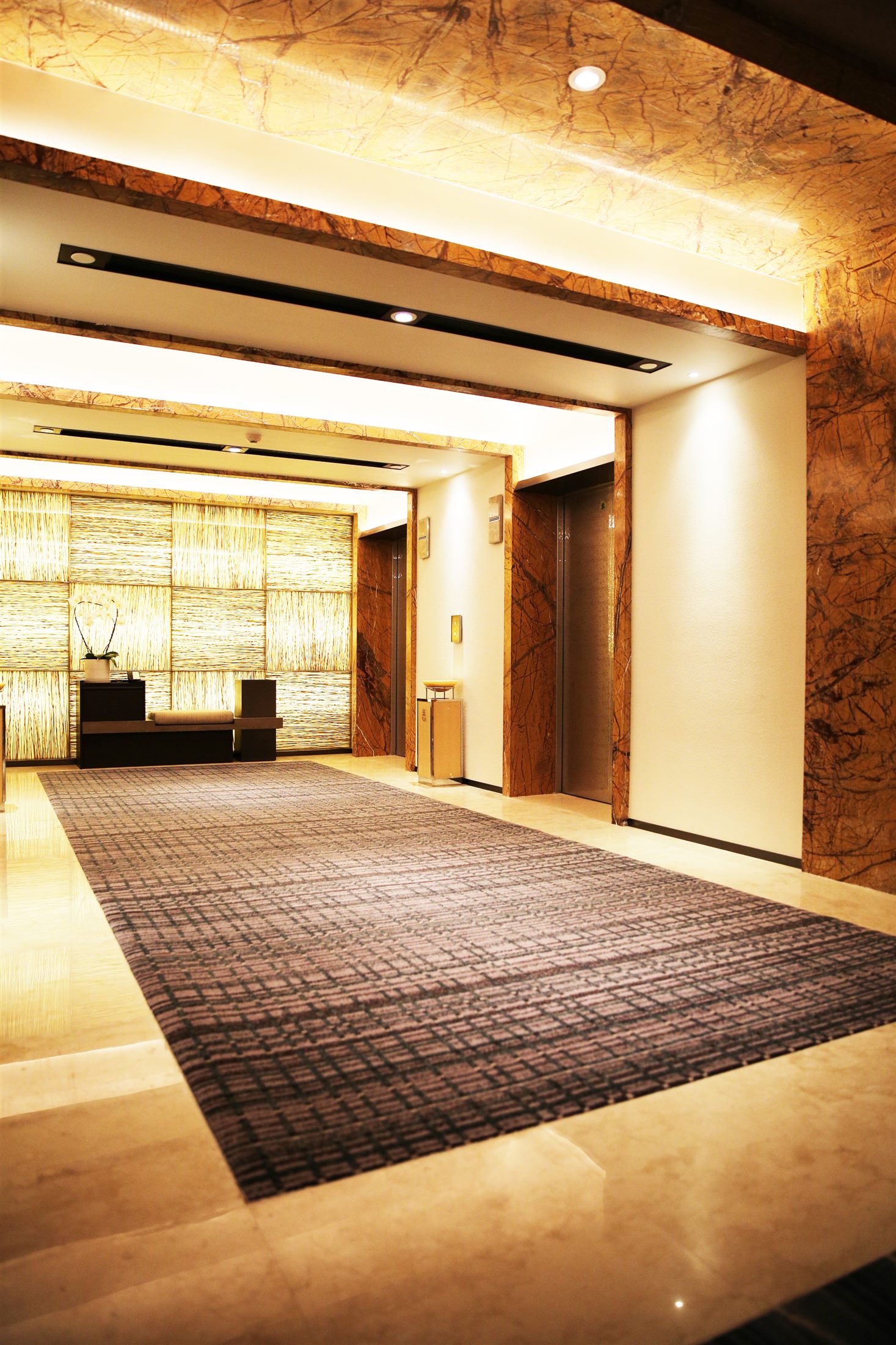 Warm lift lobby with a restrained charcoal carpet